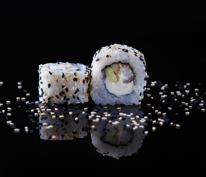 delicious sushi roll with fish and sesame on a black background with reflection Menu and restaurant concept Copy space